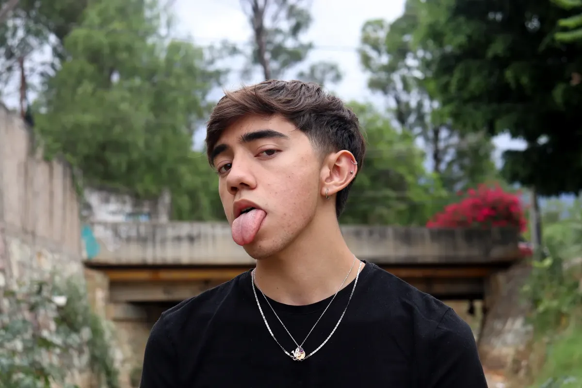 Young man posing outdoors in Mexico City with playful expression and piercings.