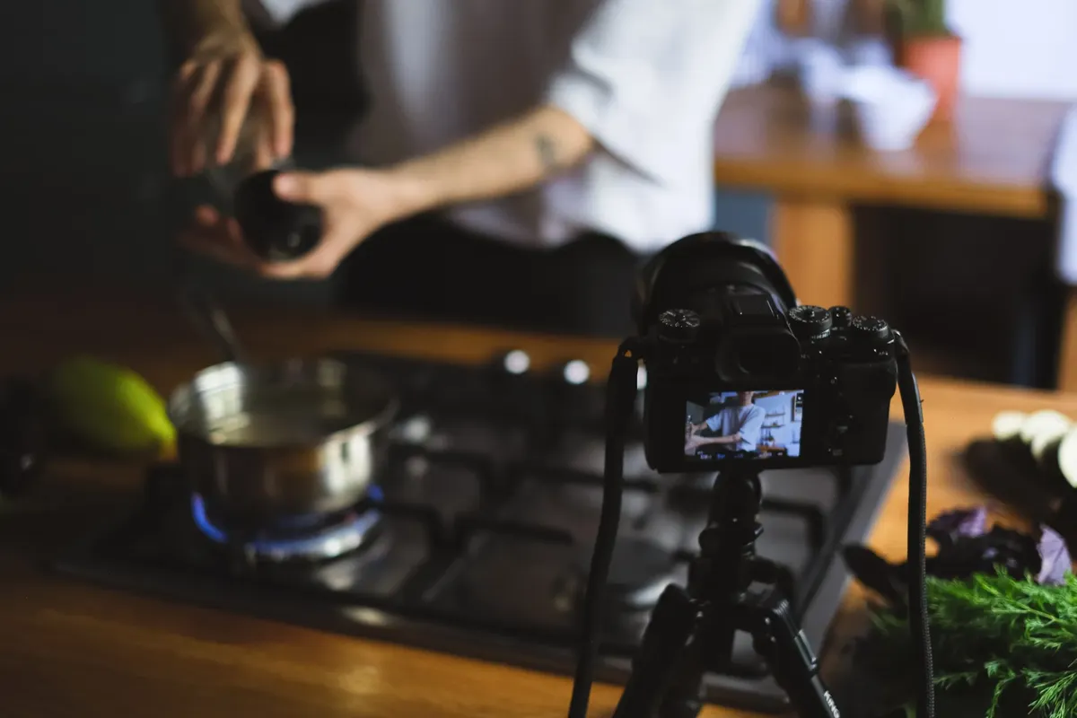 A culinary vlogger records their cooking process in a kitchen, showcasing a creative cooking setup.